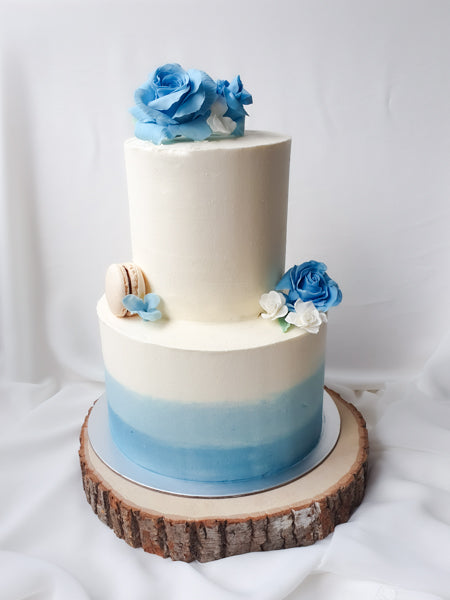Blue to white ombre two tiered cake decorated with handcrafted blue sugar roses